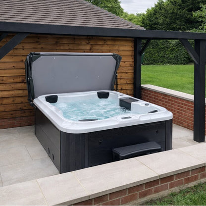 Hot tub outdoors with wooden wall and greenery