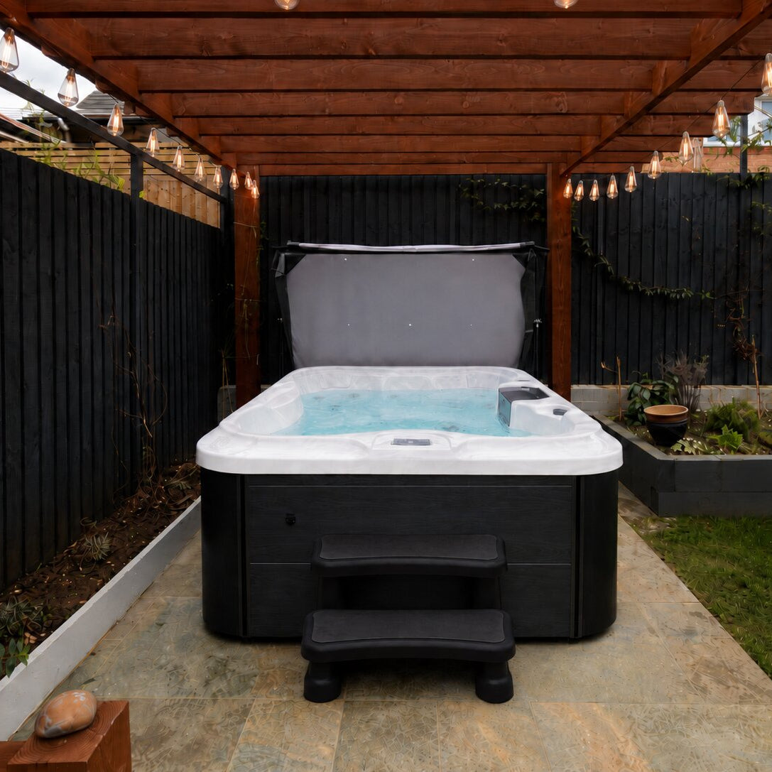 Hot tub in a backyard setting with a wooden pergola and garden elements.
