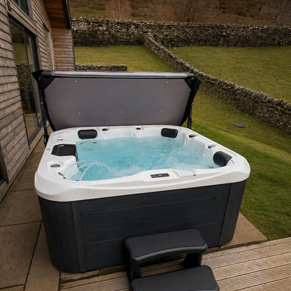 Hot tub on a wooden deck with a garden and stone wall in the background