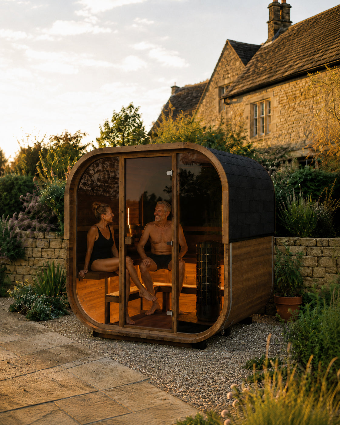 Two people inside a wooden outdoor sauna in a garden setting